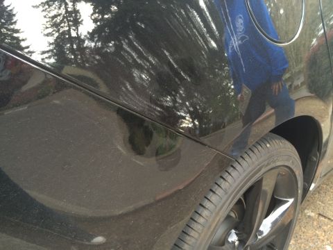 2015 Dodge Dart - Close-up view of the side panel and wheel of a black vehicle.