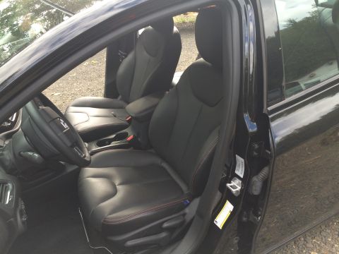 2015 Dodge Dart - The interior of a black 2015 Dodge Dart is shown, focusing on the driver's seat and steering wheel. The car features black leather seats wi…