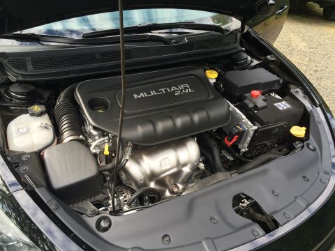 2015 Dodge Dart - The engine bay of a black 2015 Dodge Dart is shown with the hood open. The MultiAir 2.4L engine is visible, along with the battery and cool…