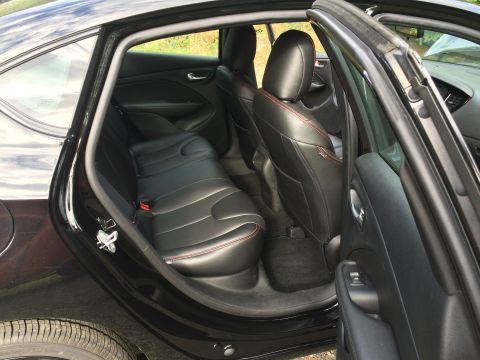 2015 Dodge Dart - The interior of a black 2015 Dodge Dart is shown, focusing on the rear passenger seats and the open driver's side rear door. The black leat…