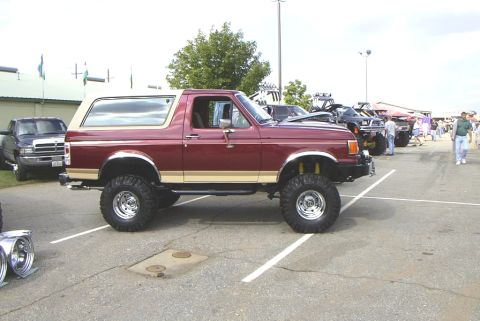 1995 Ford Bronco - This lifted Ford Bronco is parked at an outdoor event with other vehicles and attendees.