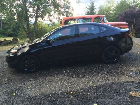 2015 Dodge Dart - A black 2015 Dodge Dart sedan is parked on a gravel driveway in front of an orange vintage truck. The car is viewed from the side, showcasi…