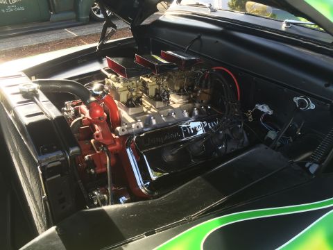 1962 Chevrolet Suburban - The engine bay of a classic car is shown, featuring a V8 engine with dual carburetors and chrome accents. The engine block is painted red,…