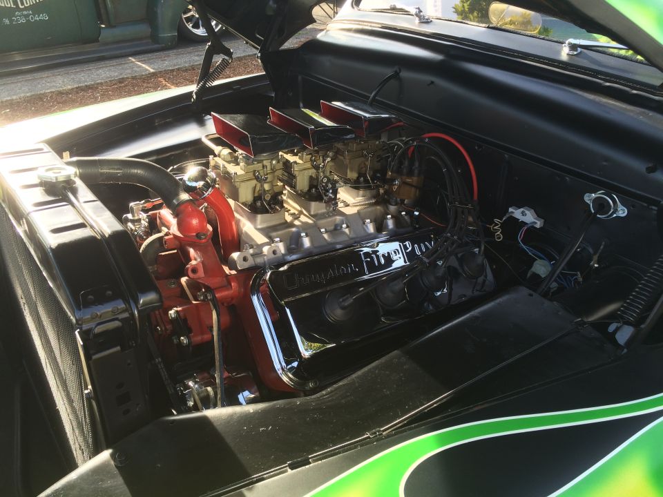 Classic V8 engine with dual carburetors, red block, and chrome valve covers.
