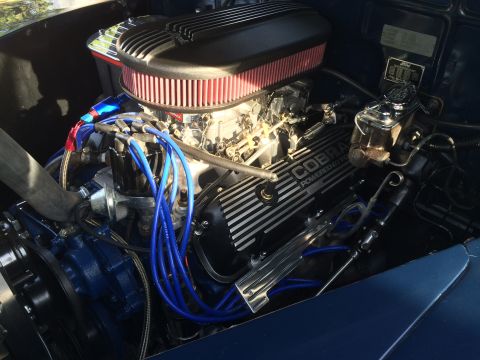 1962 Chevrolet Suburban - A detailed view of a custom engine bay, featuring a black air cleaner with a red filter, blue spark plug wires, and a black valve cover wit…