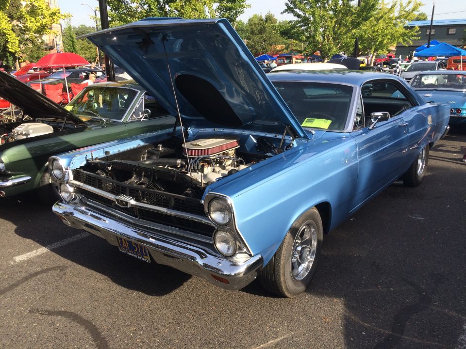 Light blue 1966 Ford Fairlane 500 with hood open, parked next to a green coupe.