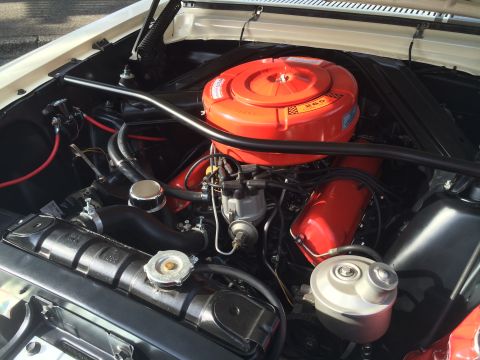 1962 Chevrolet Suburban - Close-up view of the engine bay of a classic vehicle, featuring a bright orange air cleaner assembly and red valve covers.