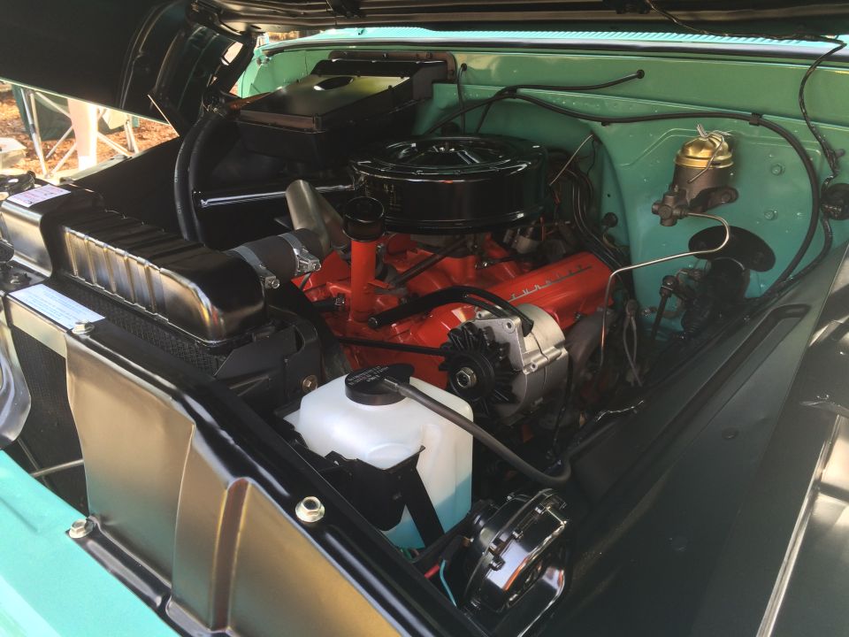 Classic Chevrolet Suburban engine bay with orange V8 engine.
