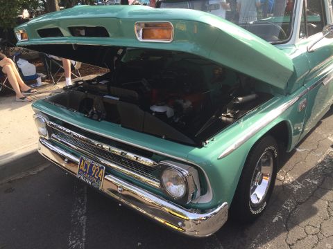 1962 Chevrolet Suburban - The front end of a teal and white 1962 Chevrolet Suburban is shown with the hood open, revealing the engine bay. The vehicle has a chrome b…