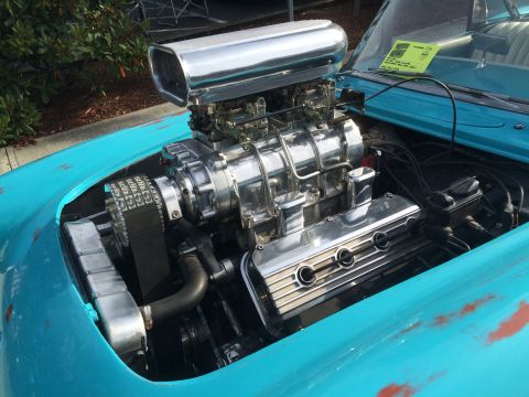 1962 Chevrolet Suburban - Close-up view of a highly polished chrome supercharger and engine components on a turquoise classic car. The engine bay is detailed with a…