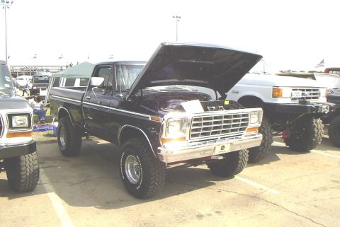 1995 Ford Bronco - Black 1979 Ford F-150 pickup truck with hood open at an outdoor event.