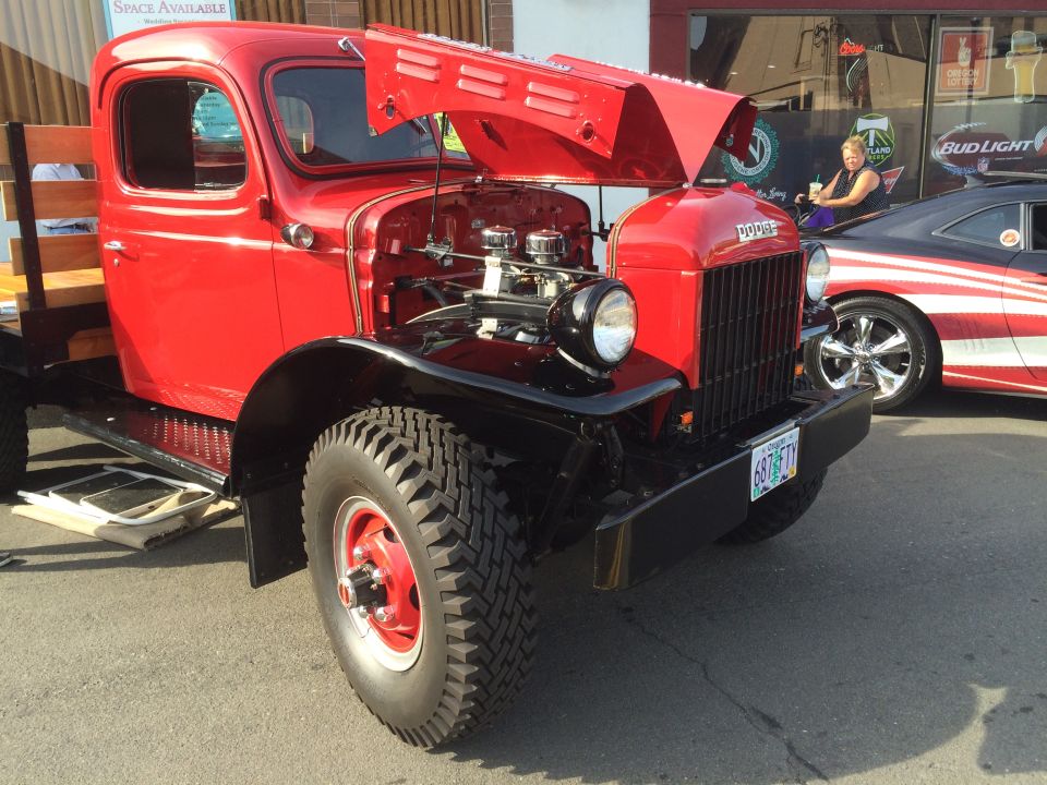 Red vintage Dodge pickup truck with hood open, parked next to a striped car.