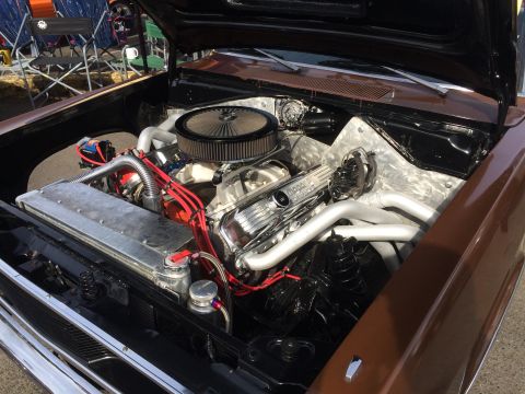 1962 Chevrolet Suburban - The engine bay of a classic brown vehicle is open, showcasing a highly modified V8 engine with a chrome air cleaner, Mopar valve covers, an…