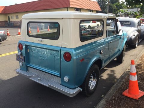 1962 Chevrolet Suburban - The rear and side of a two-tone blue and cream International Scout is parked on a street next to a sidewalk. The vehicle has a license plat…