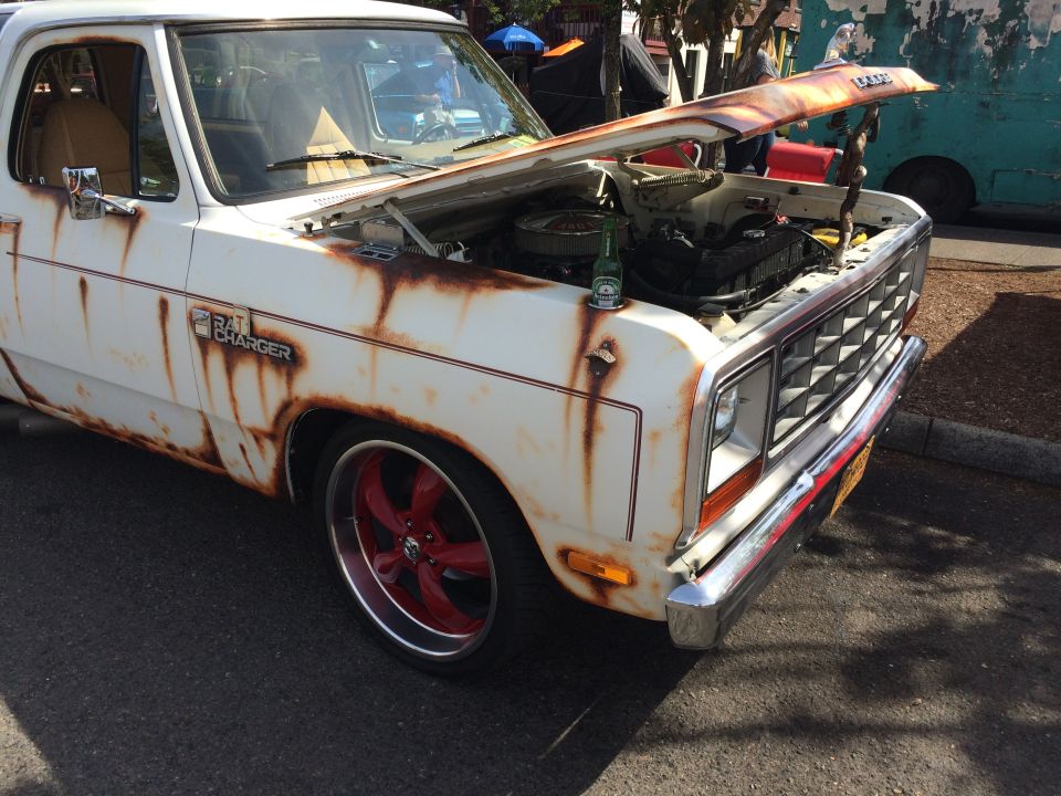 White Dodge pickup truck with rust, hood open, engine visible, beer bottle on fender.