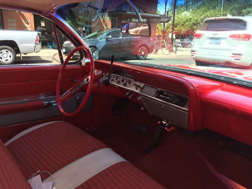 Interior of a vintage red Chevrolet with striped seats and dashboard.