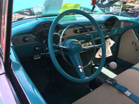 1962 Chevrolet Suburban - The interior of a classic turquoise Chevrolet is shown, featuring a turquoise steering wheel, dashboard with gauges, and tan seats with tur…