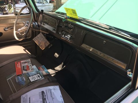 1962 Chevrolet Suburban - The interior of a vintage Chevrolet truck is shown, featuring a brown dashboard with a chrome Chevrolet emblem, a tan steering wheel, and t…