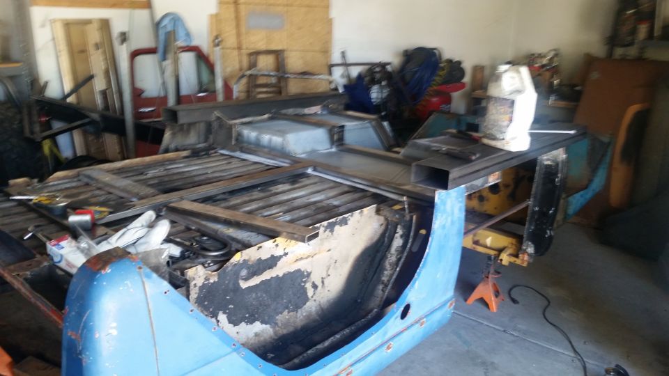 Blue vehicle frame with metal framing and tools in a garage.