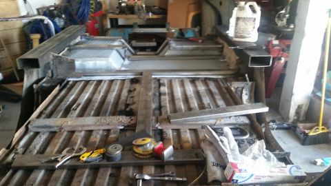 1979 Ford Bronco - The bed of a vehicle is being modified with new metal framing and floor panels. Tools and materials for welding and fabrication are laid ou…