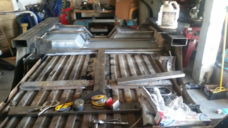 Modified vehicle bed with new metal framing, floor panels, and tools.