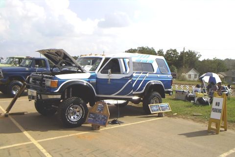 1995 Ford Bronco - A lifted Ford Bronco is displayed with its hood open at an outdoor event.