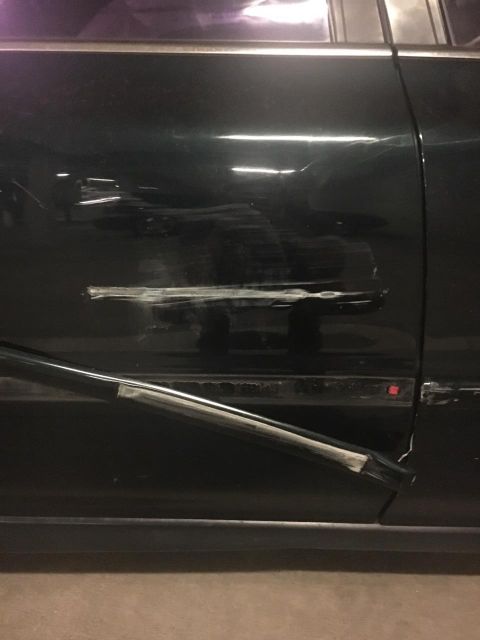 1996 Ford Bronco - Side view of a dark green car door showing significant damage and what appears to be a repair in progress.