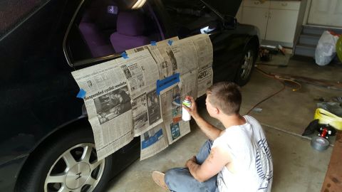 1996 Ford Bronco - A person is spray painting a car door that is covered with newspaper for protection.