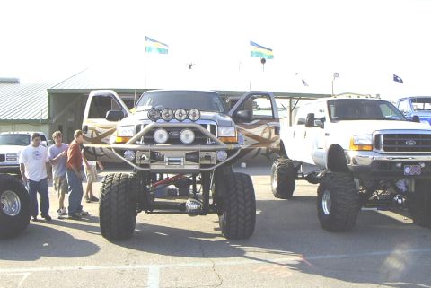 1995 Ford Bronco - Several heavily modified trucks are on display, with people gathered around.
