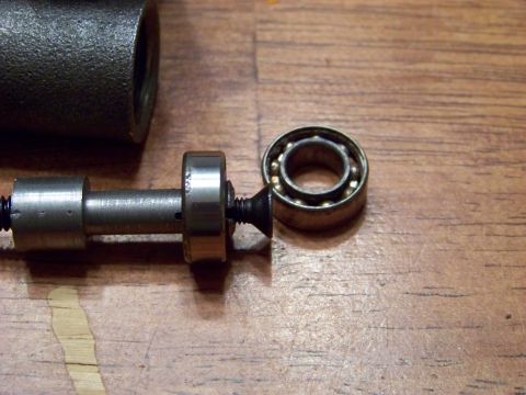 1999 Mercury Grand Marquis - A close-up view shows a metal bearing and a metal shaft with a screw thread on a wooden surface.