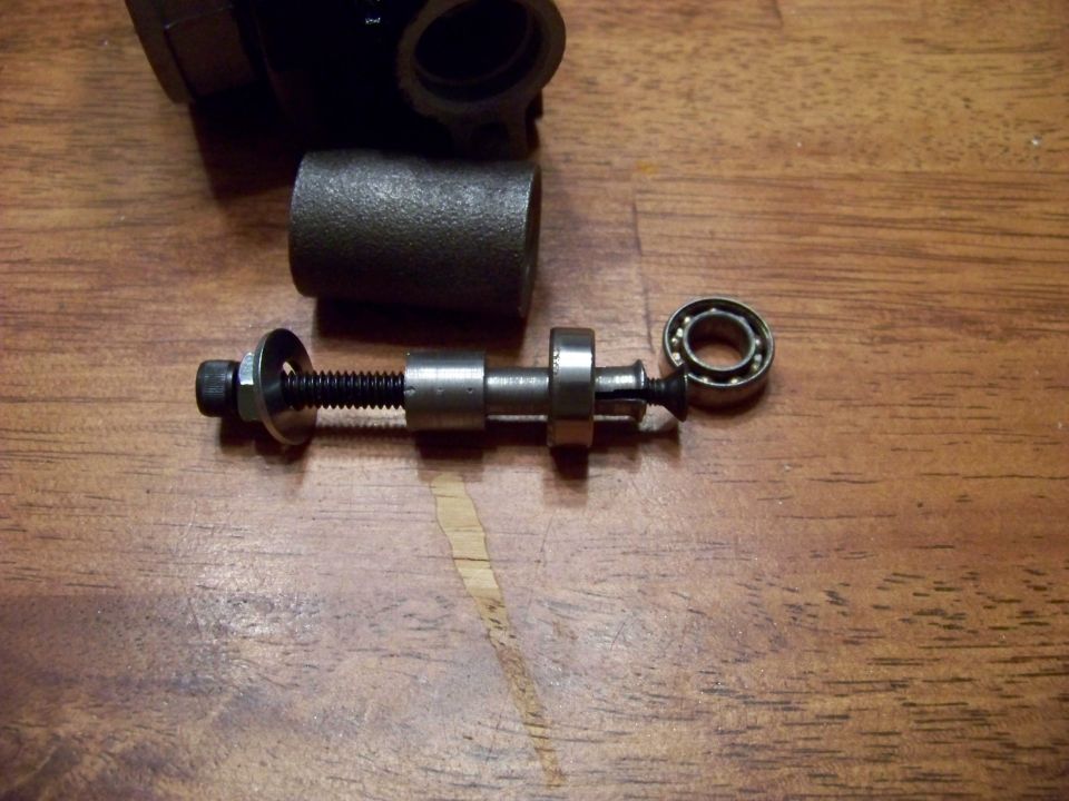 Disassembled bicycle bottom bracket assembly with bearing on wooden surface.