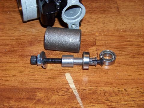 1999 Mercury Grand Marquis - A disassembled brake caliper part is shown on a wooden surface. The part includes a threaded rod with a nut, washer, and a bearing.
