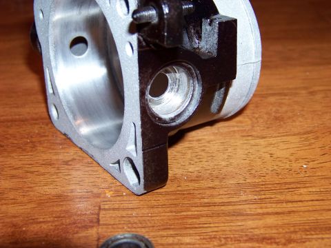 1999 Mercury Grand Marquis - A close-up, angled view of a silver and black engine part, possibly a cylinder head or manifold, resting on a wooden surface. The part feat…