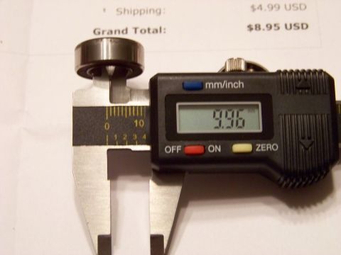 1999 Mercury Grand Marquis - A digital caliper measures a metal bearing with a reading of 9.96 mm. In the background, a document shows shipping and grand total costs.