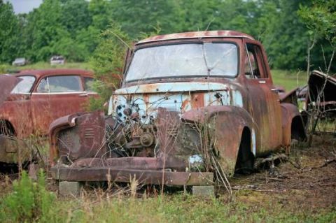 1972 Ford Bronco - An old, rusty truck sits abandoned in a field, its engine compartment exposed and overgrown with weeds.