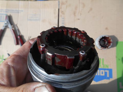 1972 Ford Bronco - Disassembled automotive part with gears and springs, covered in oil, held in hand.
