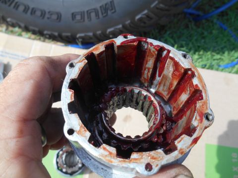 1972 Ford Bronco - A close-up view of a disassembled vehicle component, covered in red grease, with a tire visible in the background.
