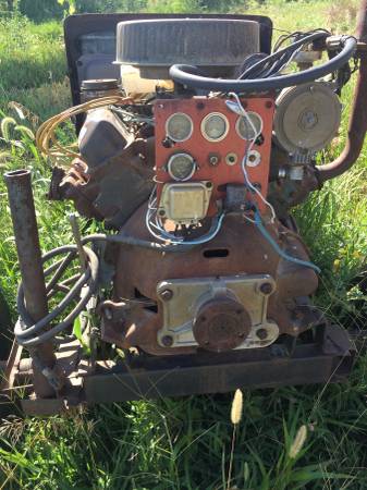 1973 Ford F-100 - An old engine with a red panel of gauges sits in a grassy field.