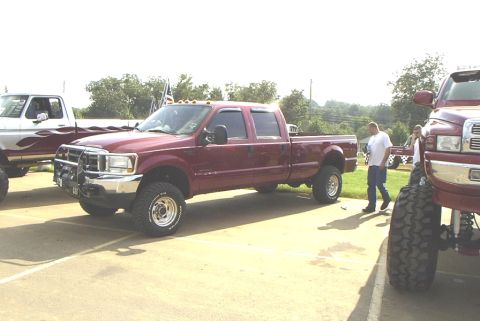 1995 Ford Bronco - Maroon crew cab pickup truck parked outdoors, with another truck visible to the left.