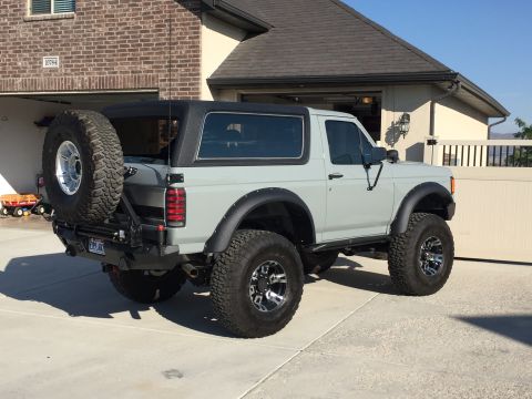 1988 Ford Bronco - This gray Ford Bronco is shown from a rear-three-quarter angle, parked in a driveway.