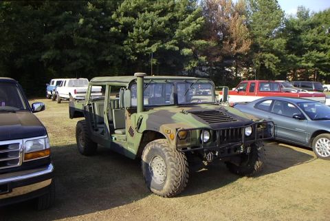 1995 Ford Bronco - Military Humvee with camouflage paint parked at an outdoor event with other vehicles visible.