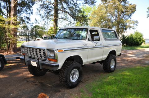1979 Ford Bronco - This lifted 1978 Ford Bronco features a distinctive chrome grille and large off-road tires, presented in a 3/4 front view.