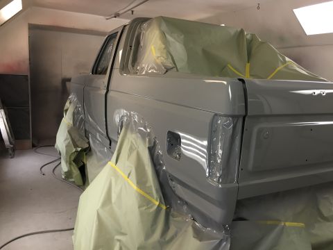 1988 Ford Bronco - Ford Bronco in a paint booth, undergoing restoration with masking covering most of the body.