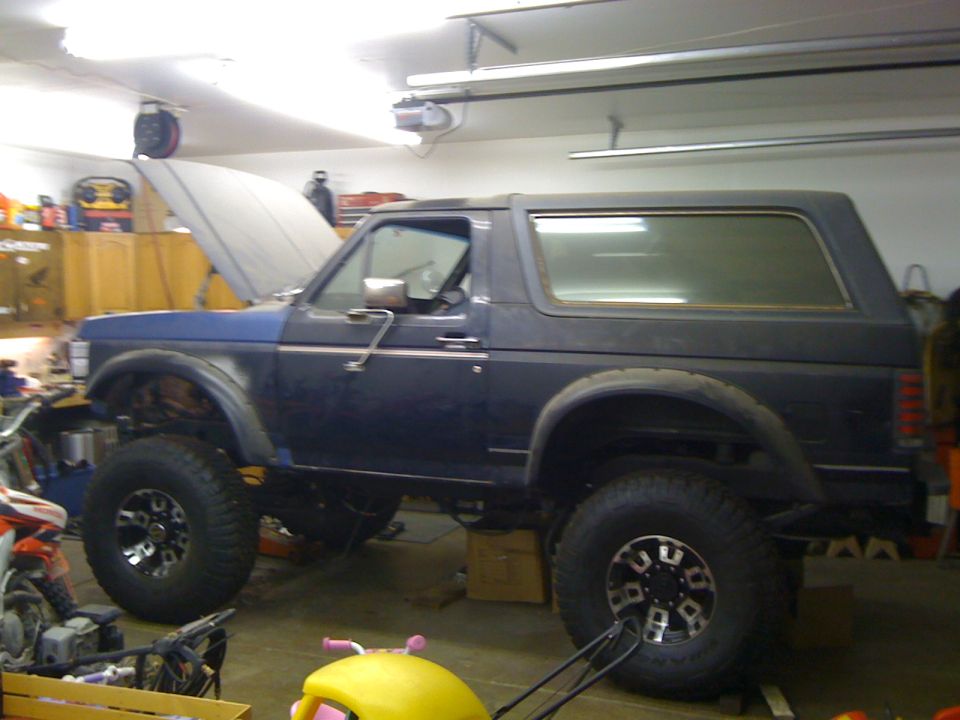 Side view of a lifted 1988 Ford Bronco in a garage