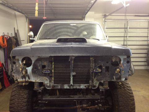 1988 Ford Bronco - Front view of a 1988 Ford Bronco undergoing repairs in a garage, missing headlights and grille.