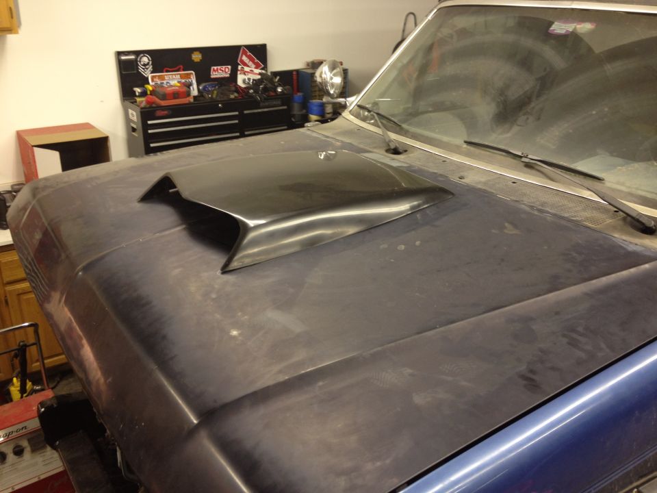 Car hood with a black scoop installed. Toolbox and garage in background