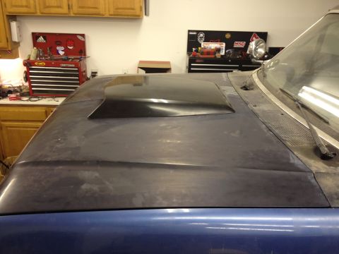 1988 Ford Bronco - A blue vehicle's hood, fitted with a black scoop, sits in a garage with tool chests in the background.