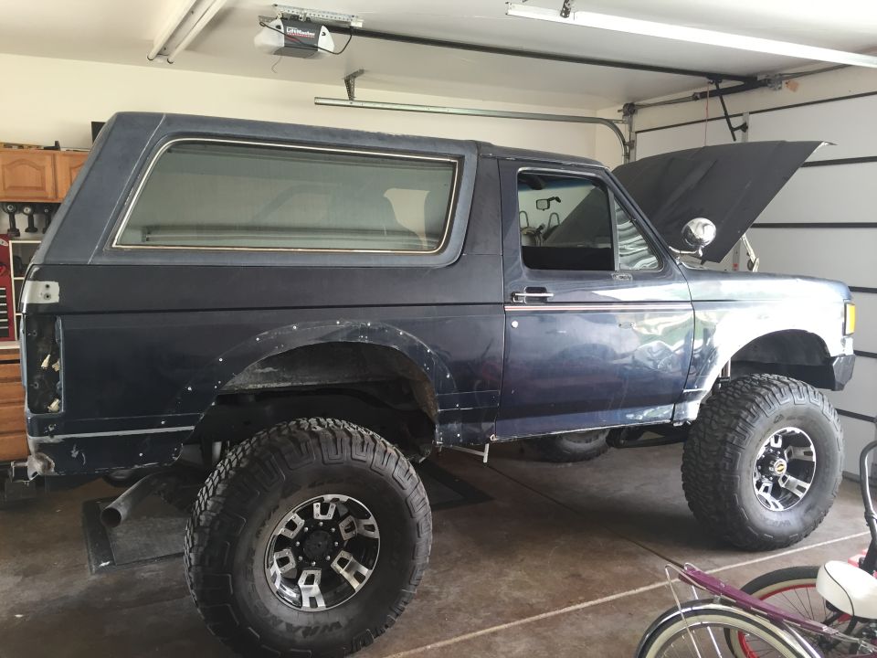 Dark blue SUV with hood up, lifted suspension, and aftermarket wheels