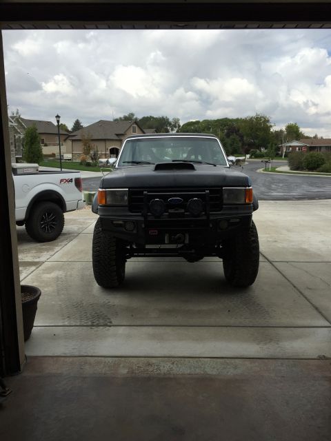 1988 Ford Bronco - A black SUV with a lifted suspension and off-road modifications is parked in a driveway.