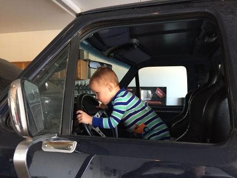 1988 Ford Bronco - A young child pretends to drive while sitting in the driver's seat of a vehicle.